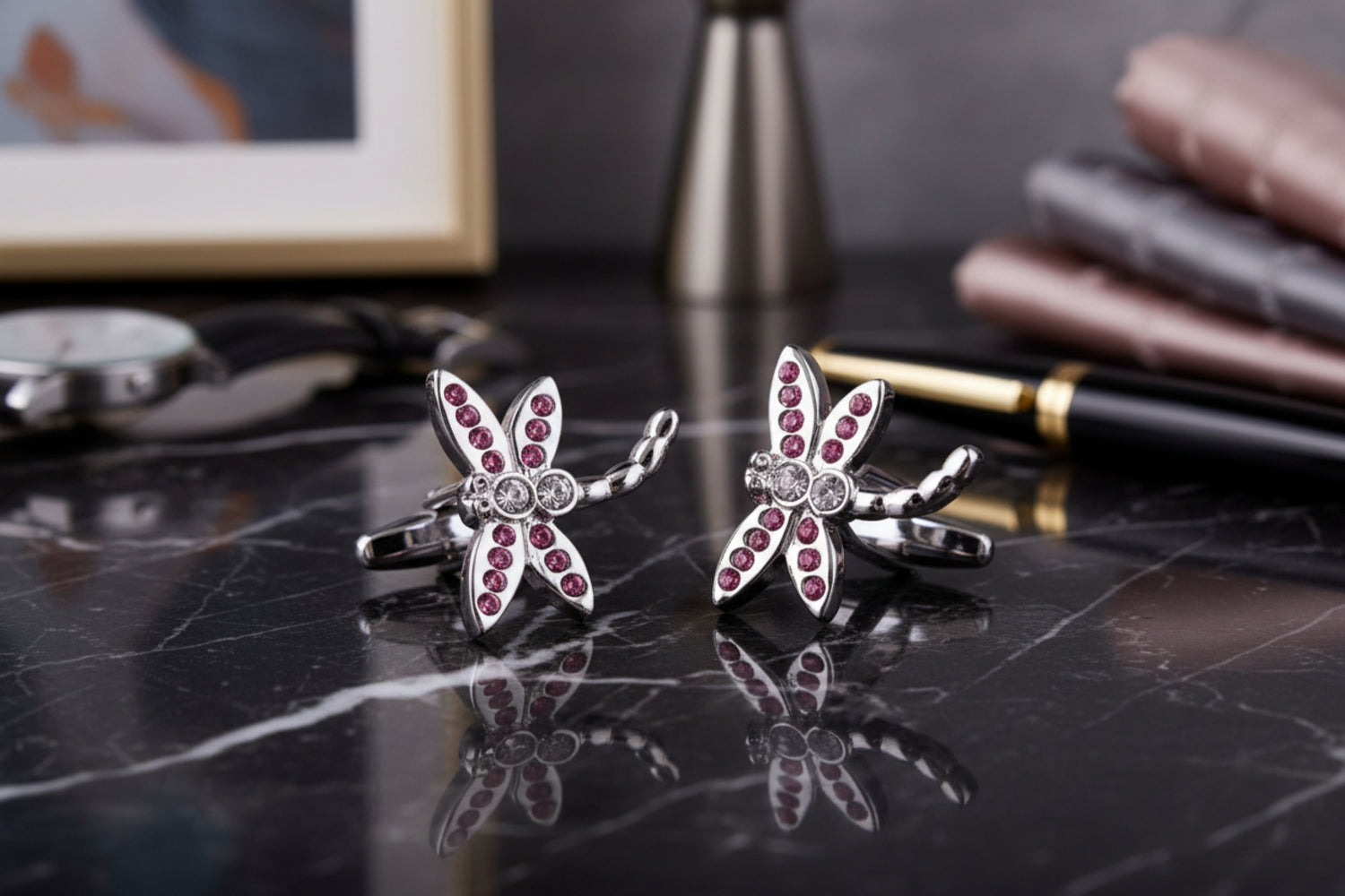 A chrome and pink color dragonfly shape pair of cuff-links.