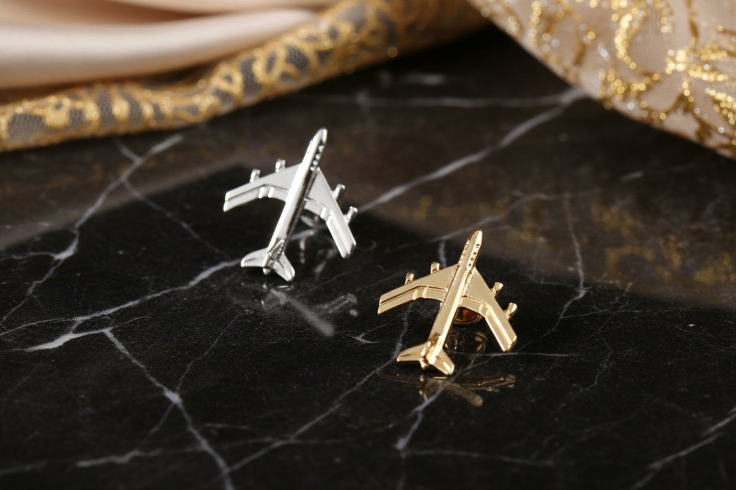 Showing two airplane shaped lapel pins: gold and silver