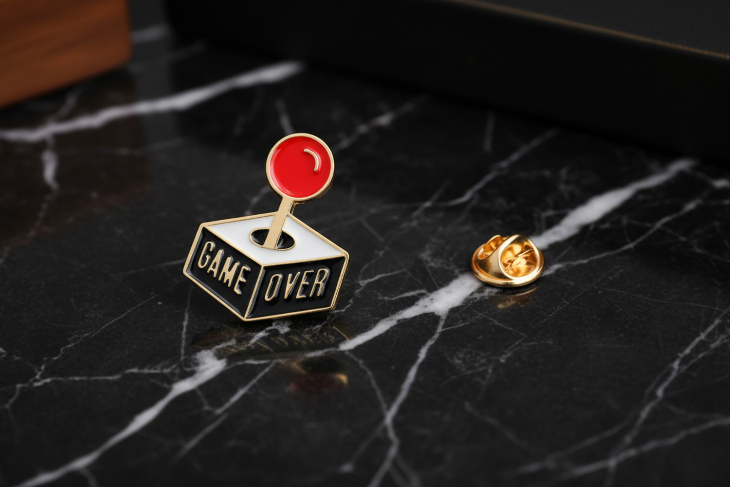 A joystick shaped lapel pin that says, "Game Over" on the side of the lapel pin